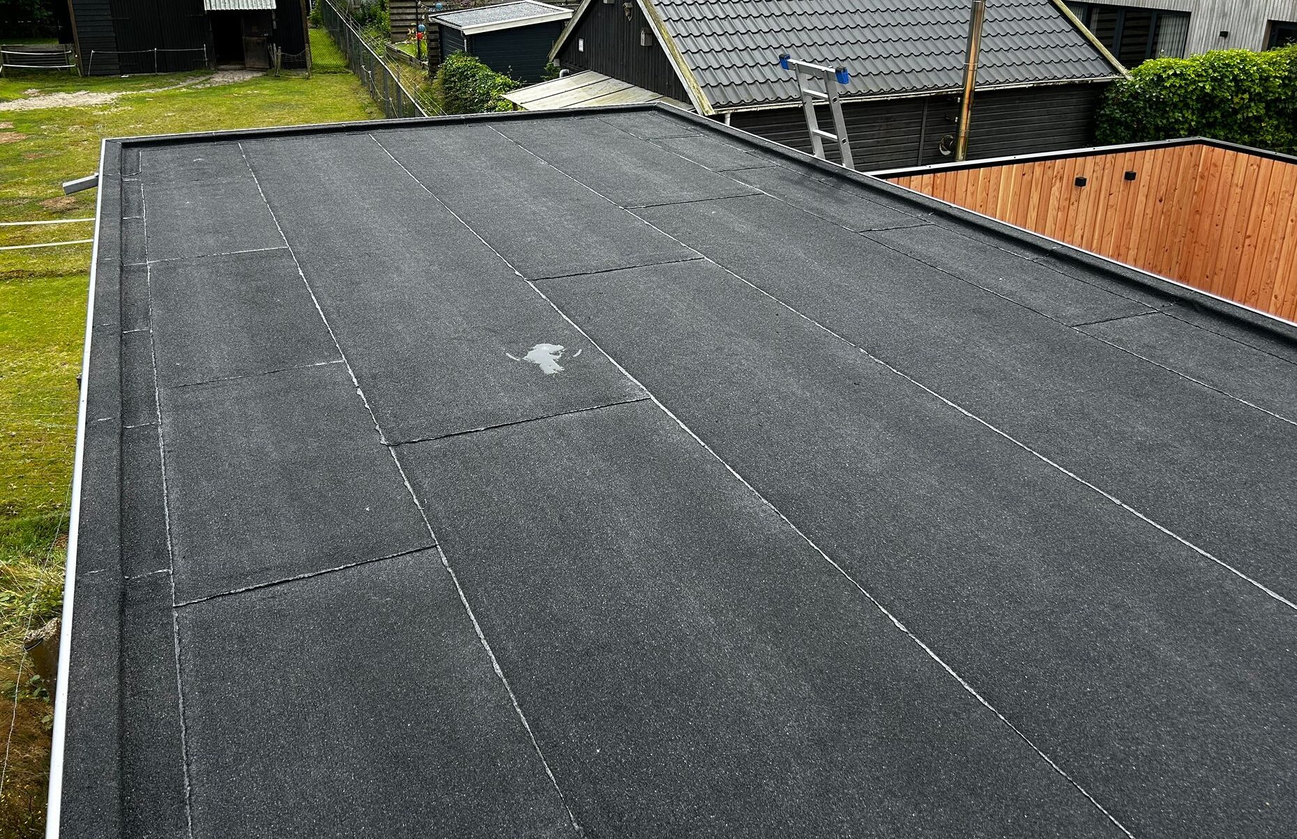 zwarte bitumen toplaag (dakleer) op overkapping