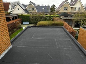 Nieuwe bitumen toplaag op plat dak van garage