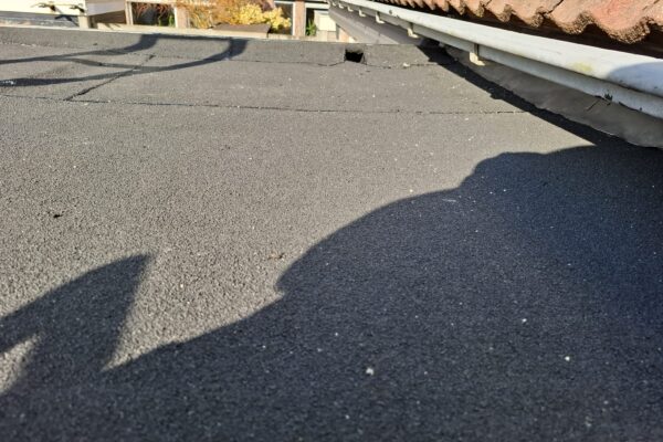 Het uitgevlakte dak met de nieuwe bitumen toplaag met afschot waardoor water via de uitloop weg kan