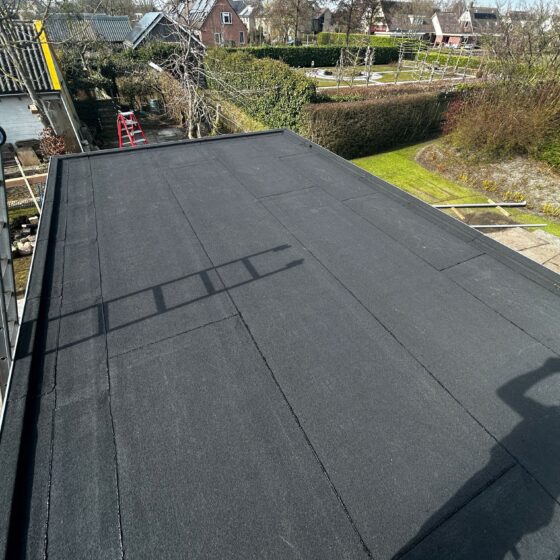Het platte dak van een terrasoverkapping met een nieuwe bitumen toplaag