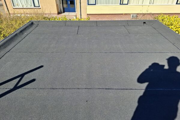 nieuwe bitumen toplaag over bestaande dakbedekking van tuinhuis gebrand