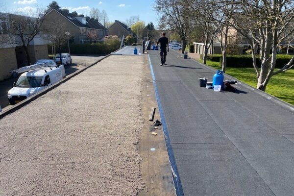 Aanbrengen van een nieuwe bitumen onderlaag en toplaag (dakleer) op een gemeenschappelijke carport